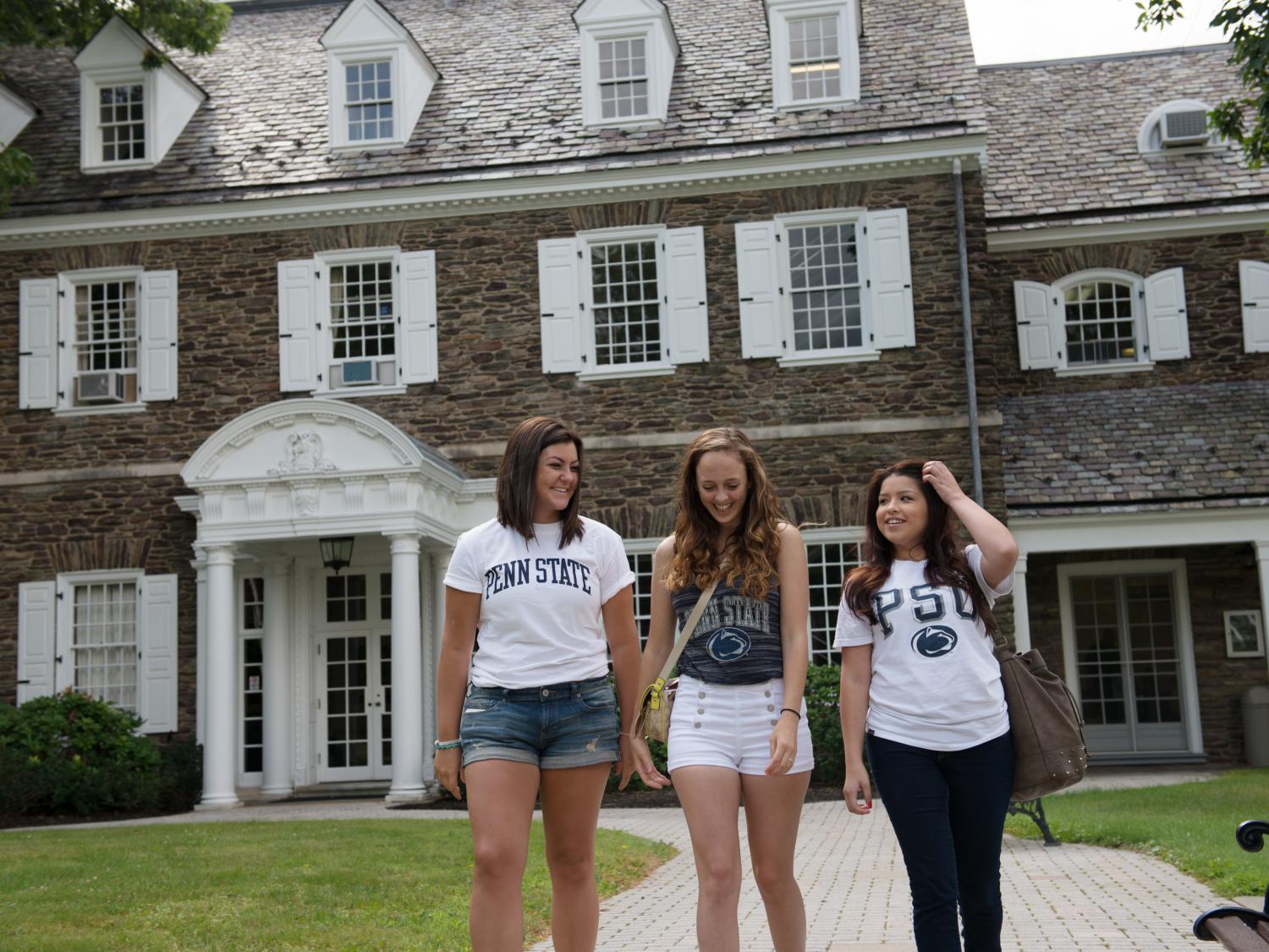 Penn State Wilkes-Barre female students walking in front of Hayfield House and laughing
