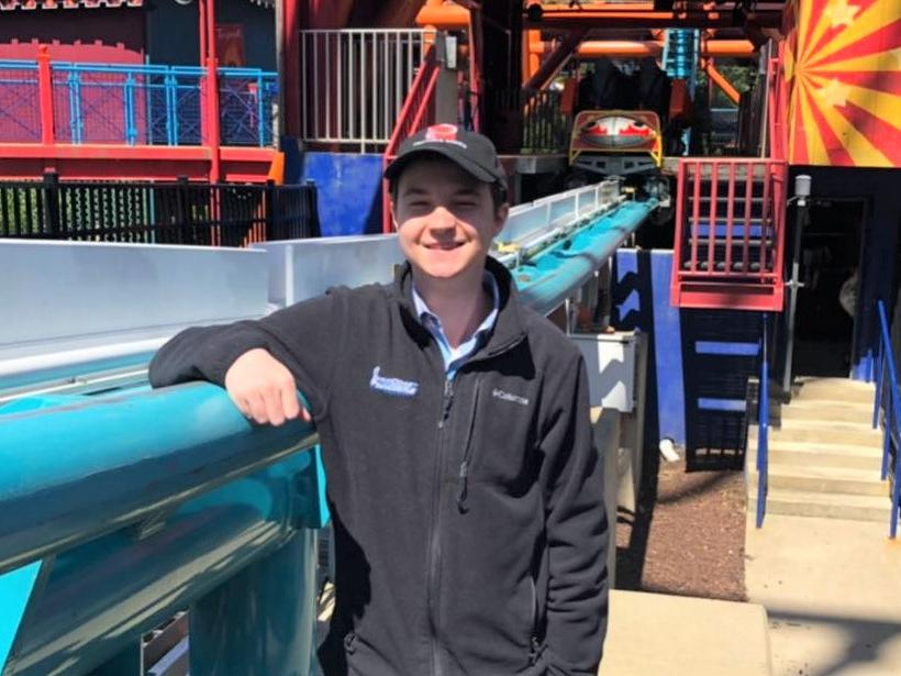 Penn State Behrend graduate William Friedlander stands next to a roller coaster track.