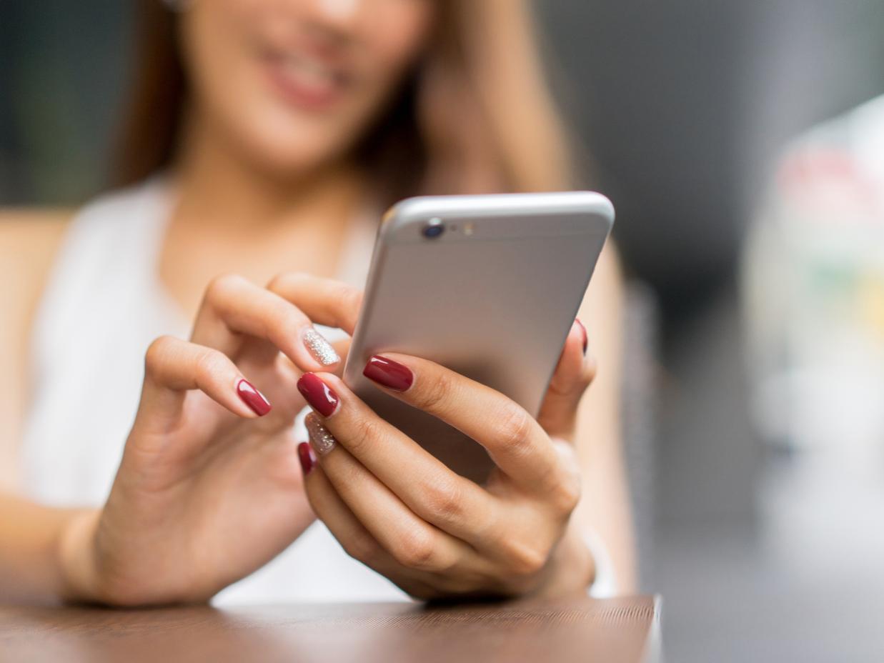A woman with blonde hair uses a smartphone