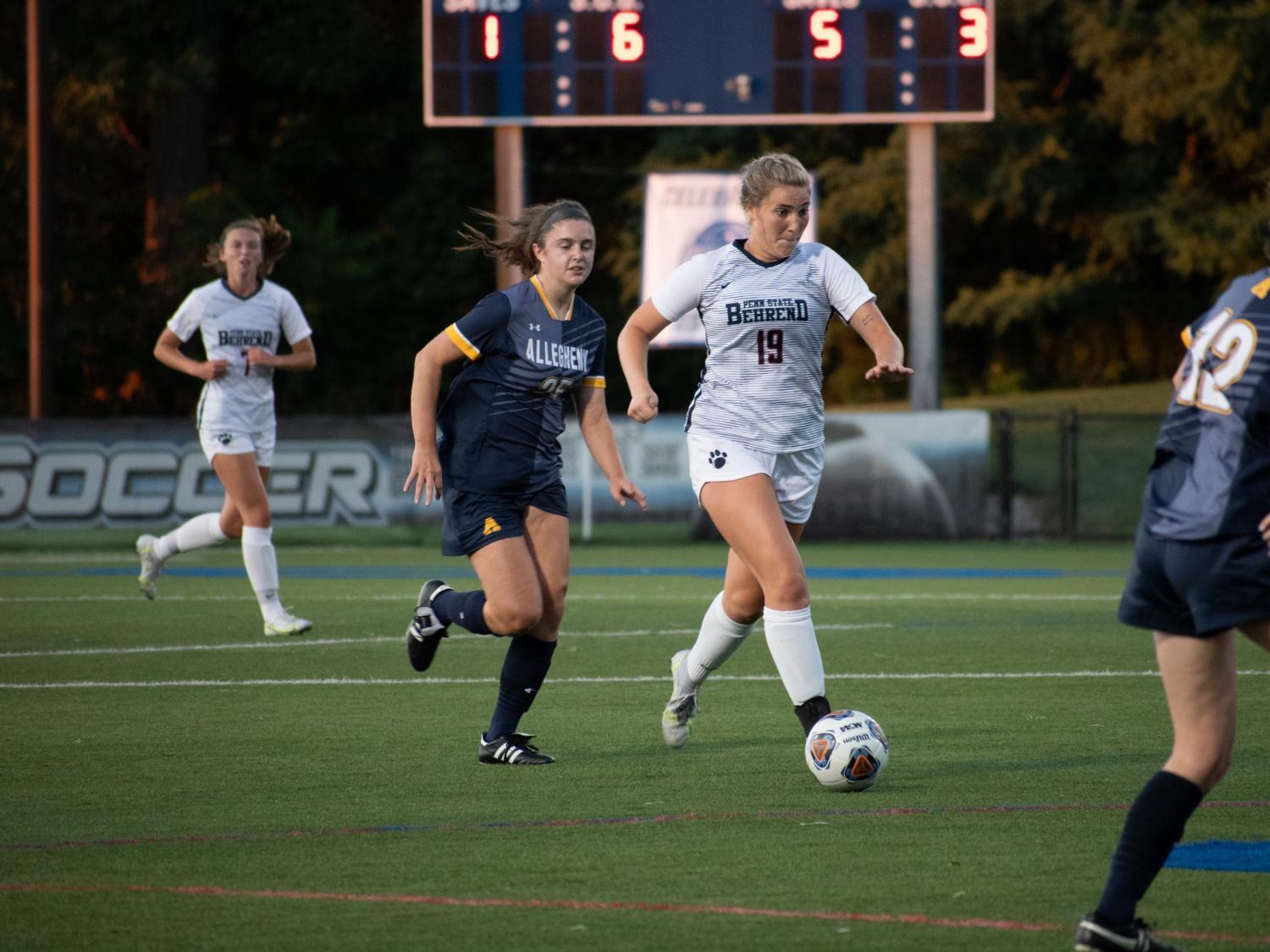 A Penn State Behrend women's soccer player kicks the ball downfield.