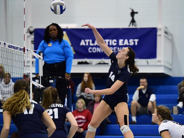 A Penn State Behrend women's volleyball player spikes the ball.