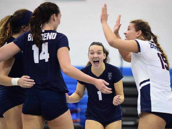 Penn State Behrend volleyball players celebrate after scoring a point.