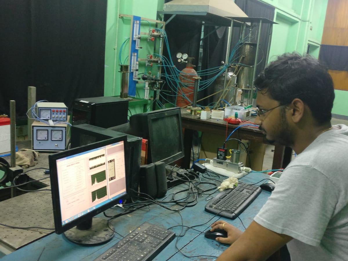 Indian man works on computer, monitoring machinery.