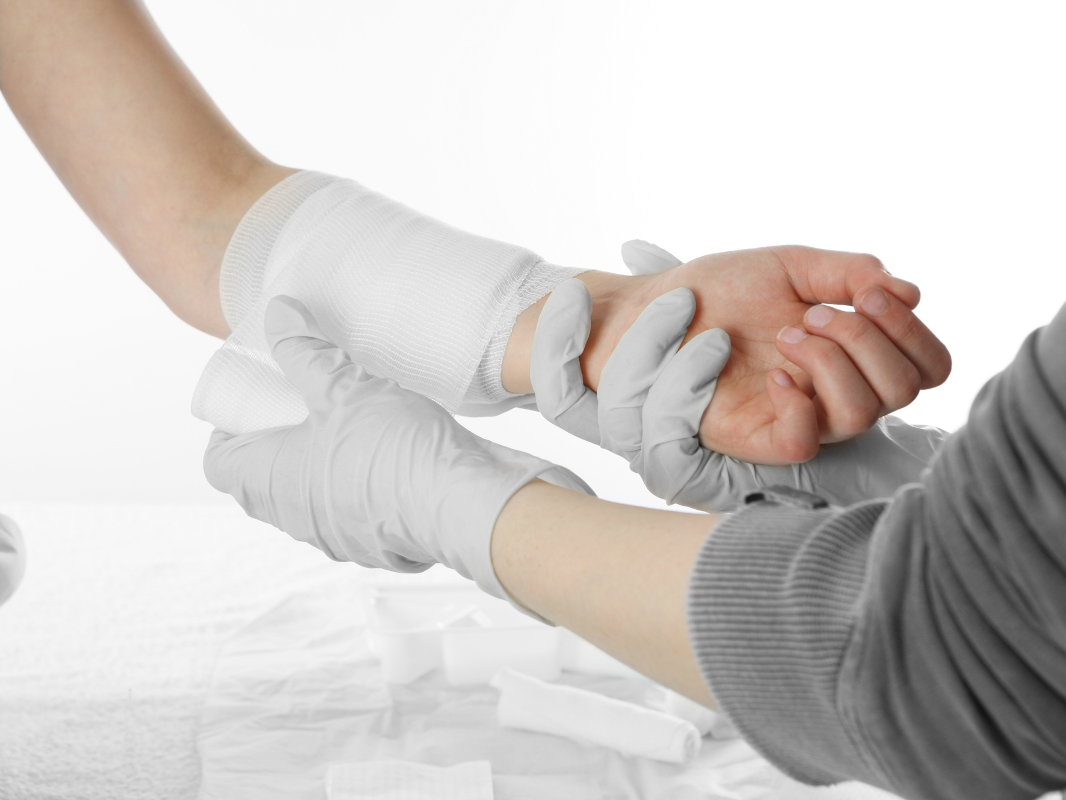 A close up of a provider dressing a patient's arm wound