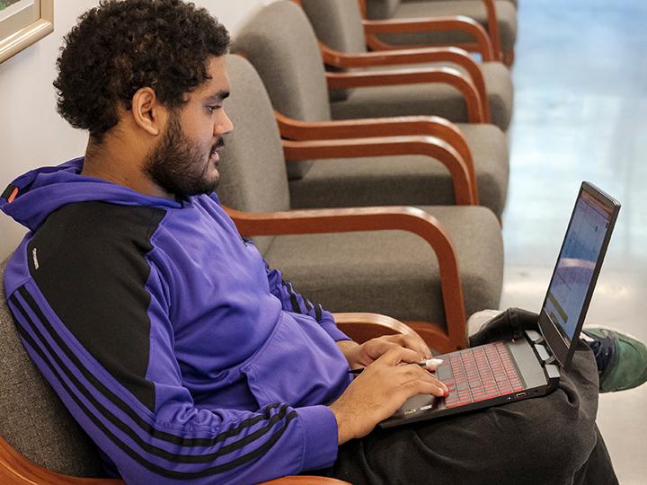 a student works on his laptop in a study space in Gaige