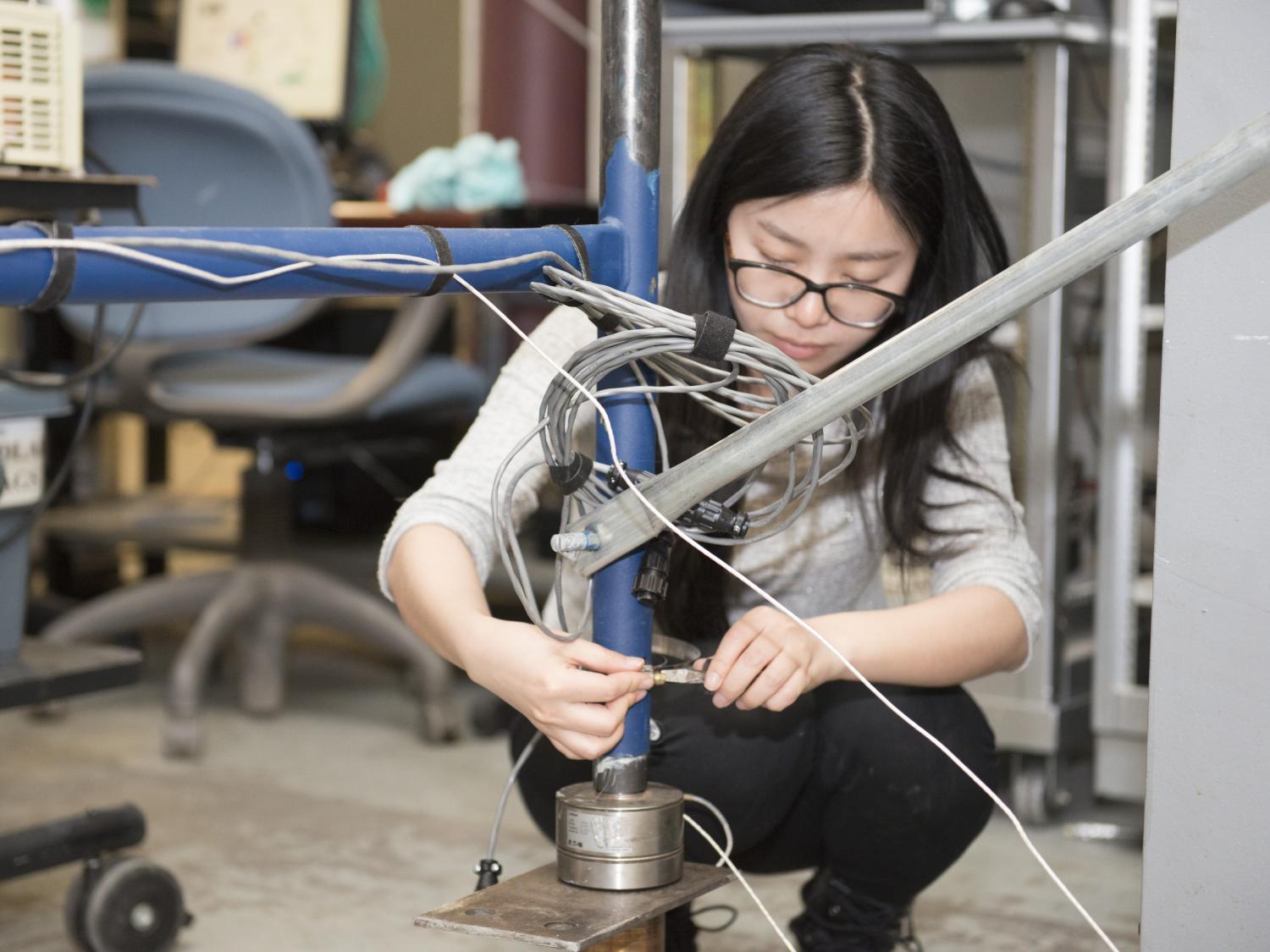 Xiao Yuan clamps wires to a temporary structure