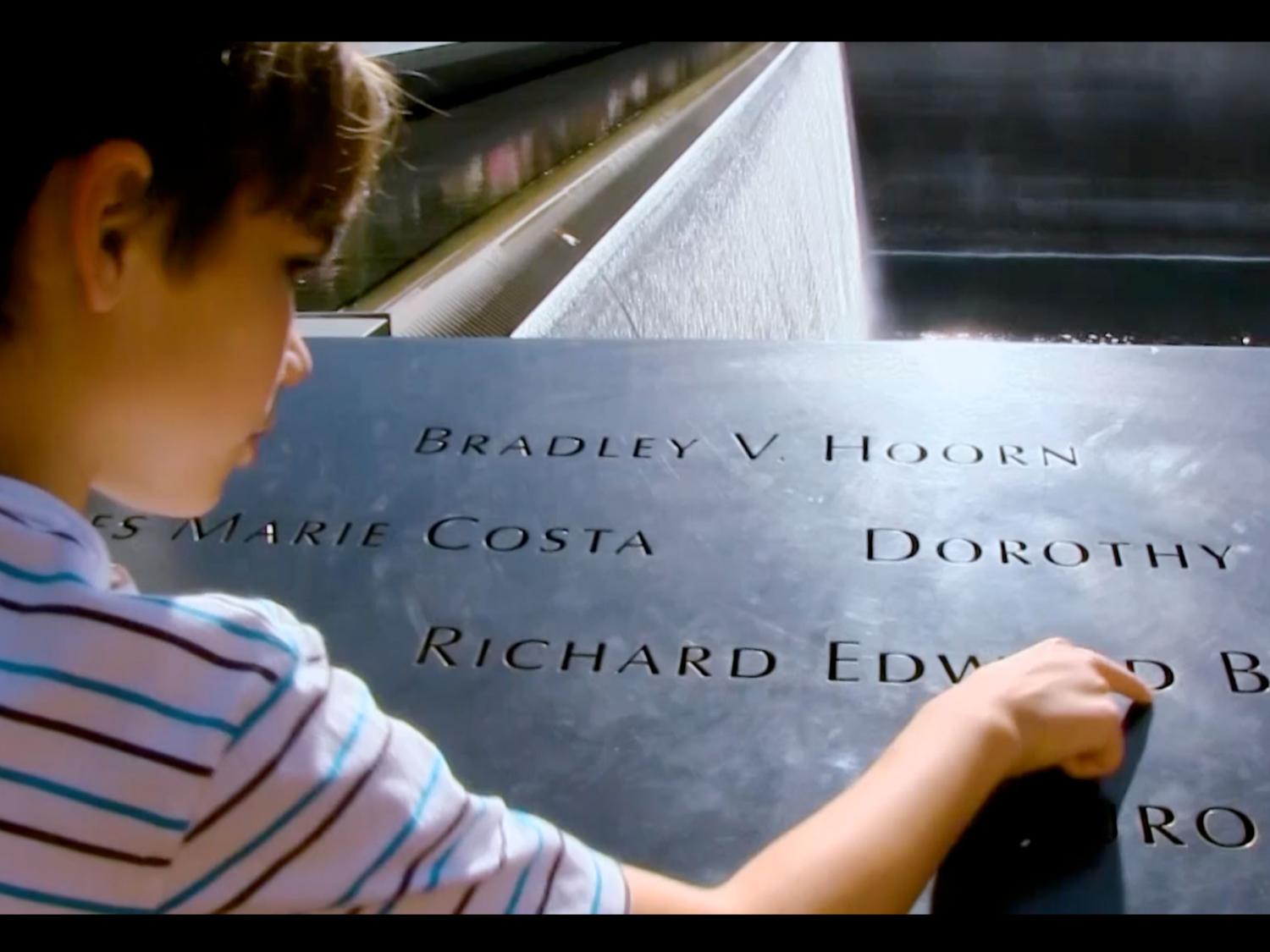 A closeup of a young boy touching the September 11 memorial.