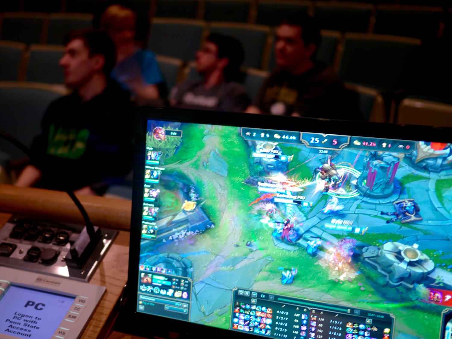 League of Legends gameplay on a computer screen with people sitting in the background