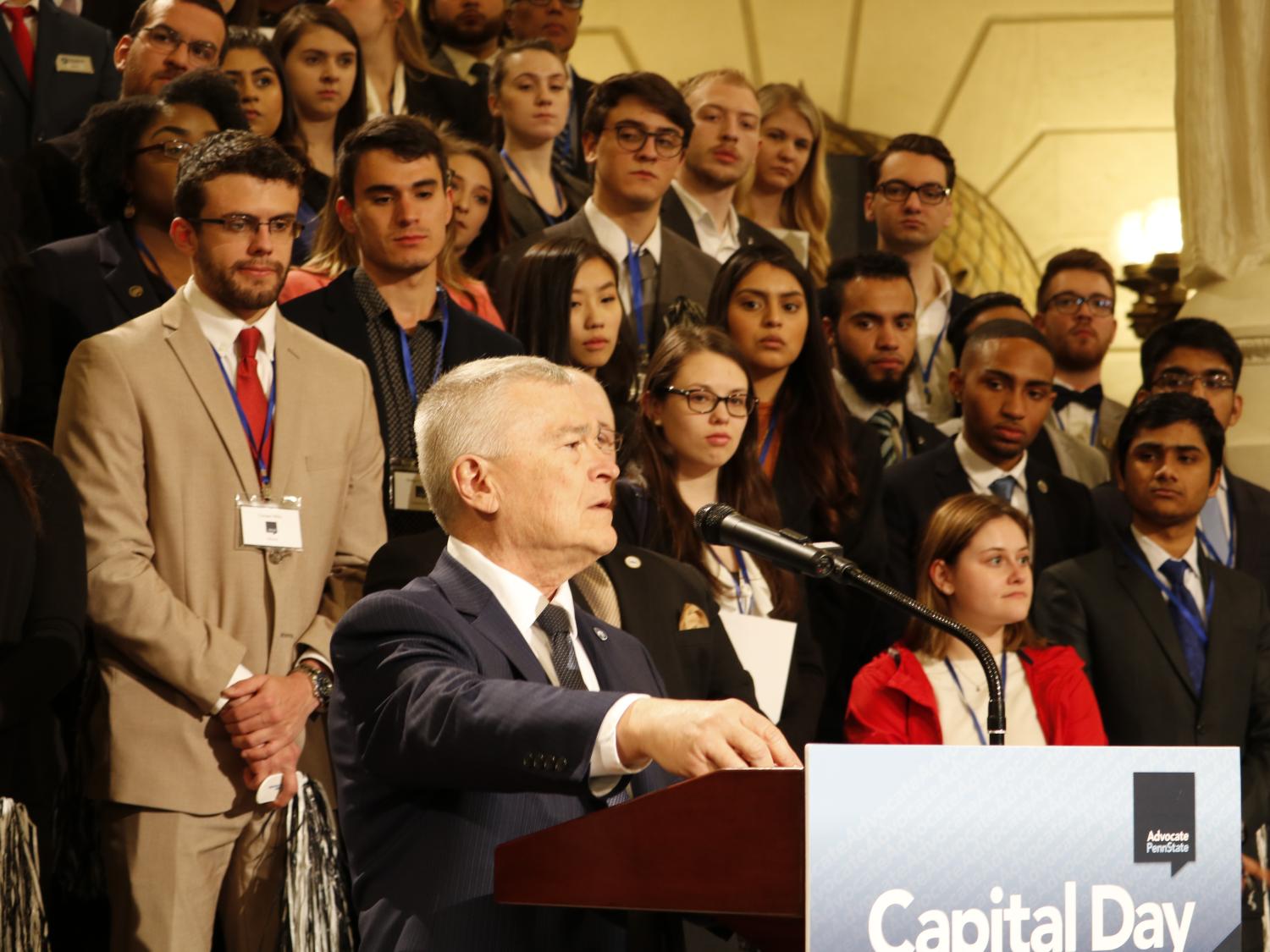 man at podium with students standing behind him