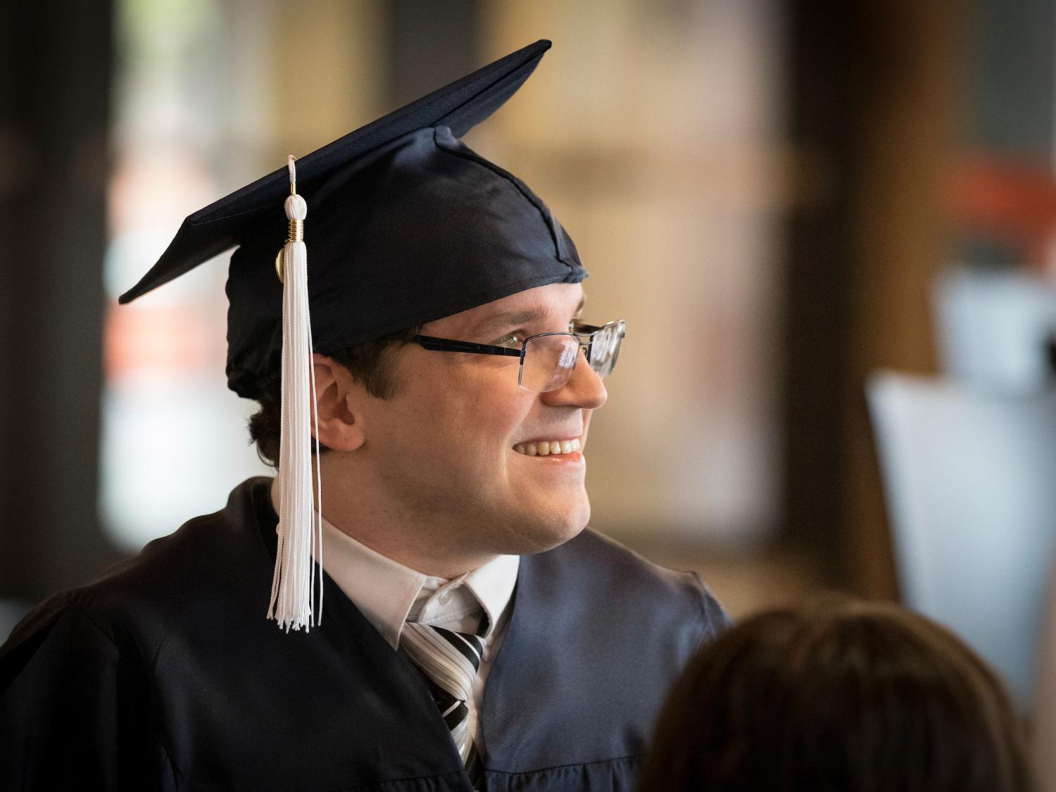 man with graduation cap on looking off into distance
