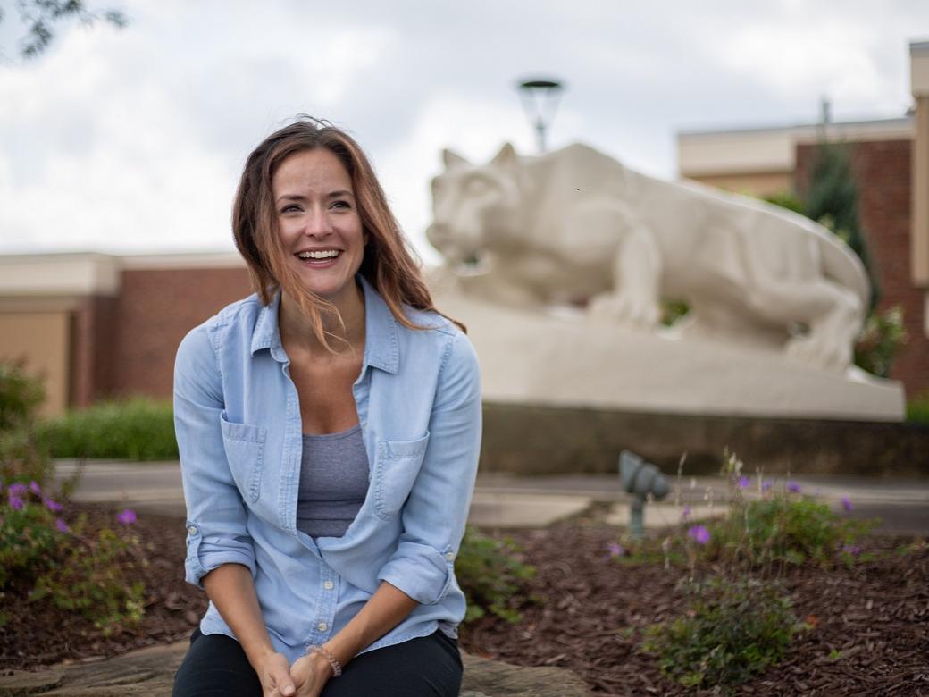 Woman sits in front of Nittany Lion Shrine