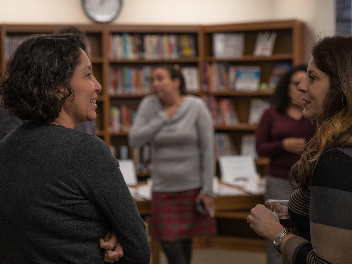 Two women stand and talk in library