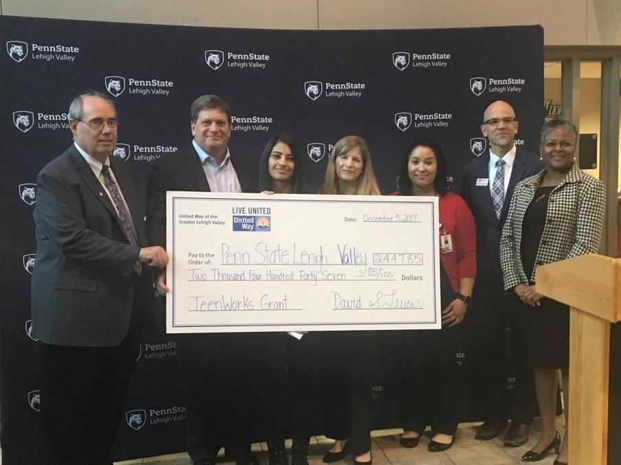 people standing with big check at presentation