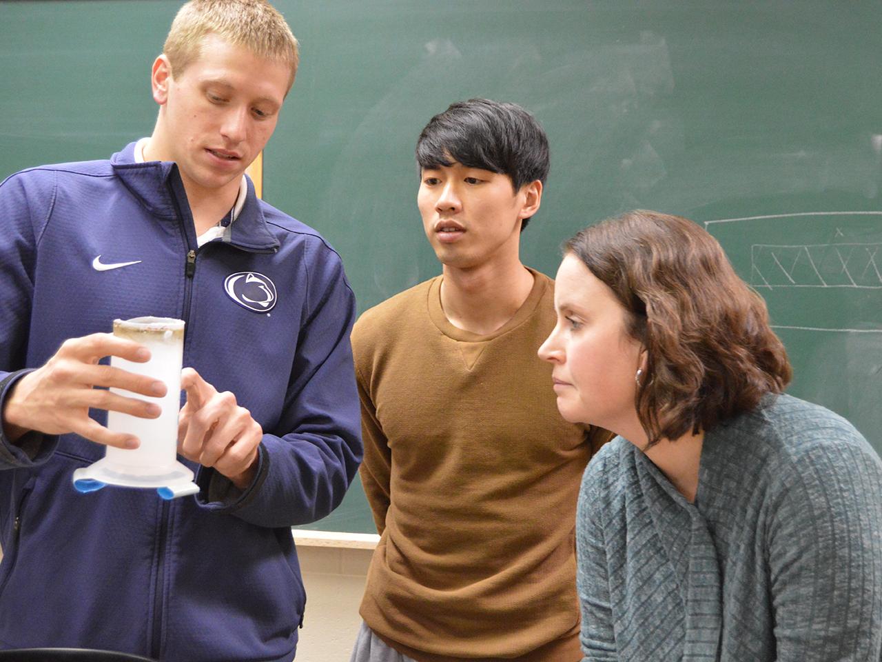 students showing component of rain gauge to professor Amy Huff