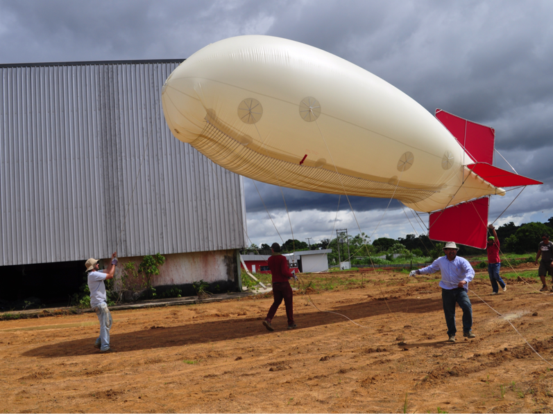 people walking a tethered research blimp