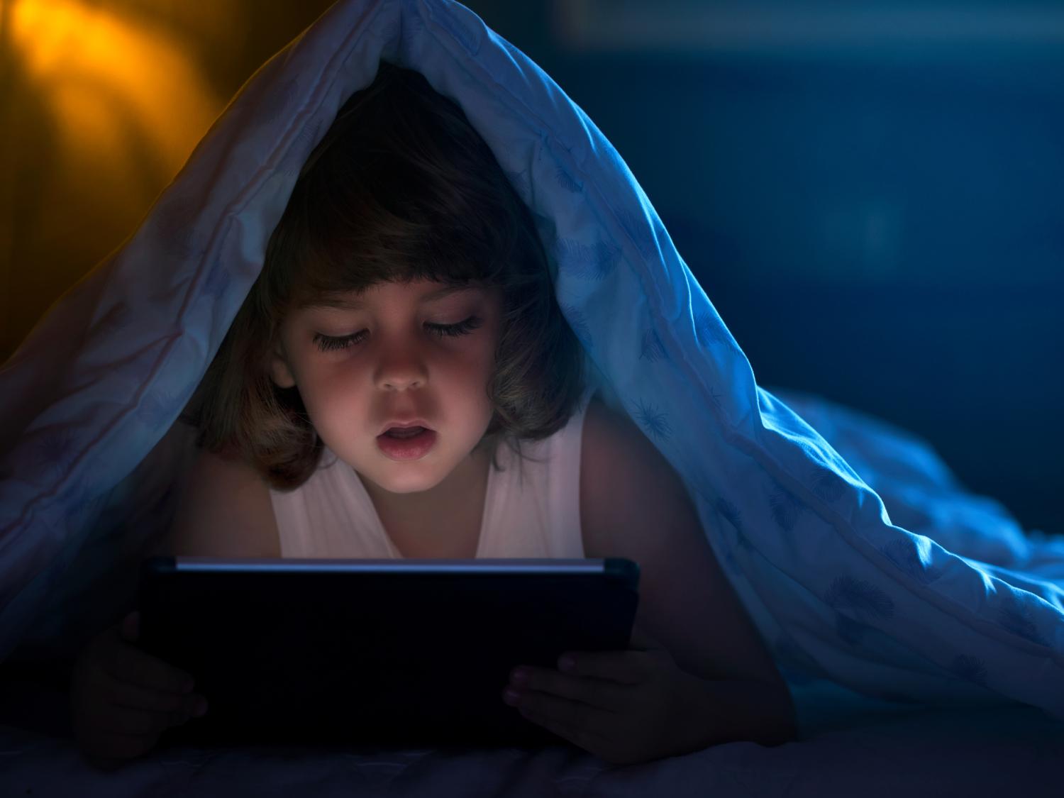 child under cover with ipad