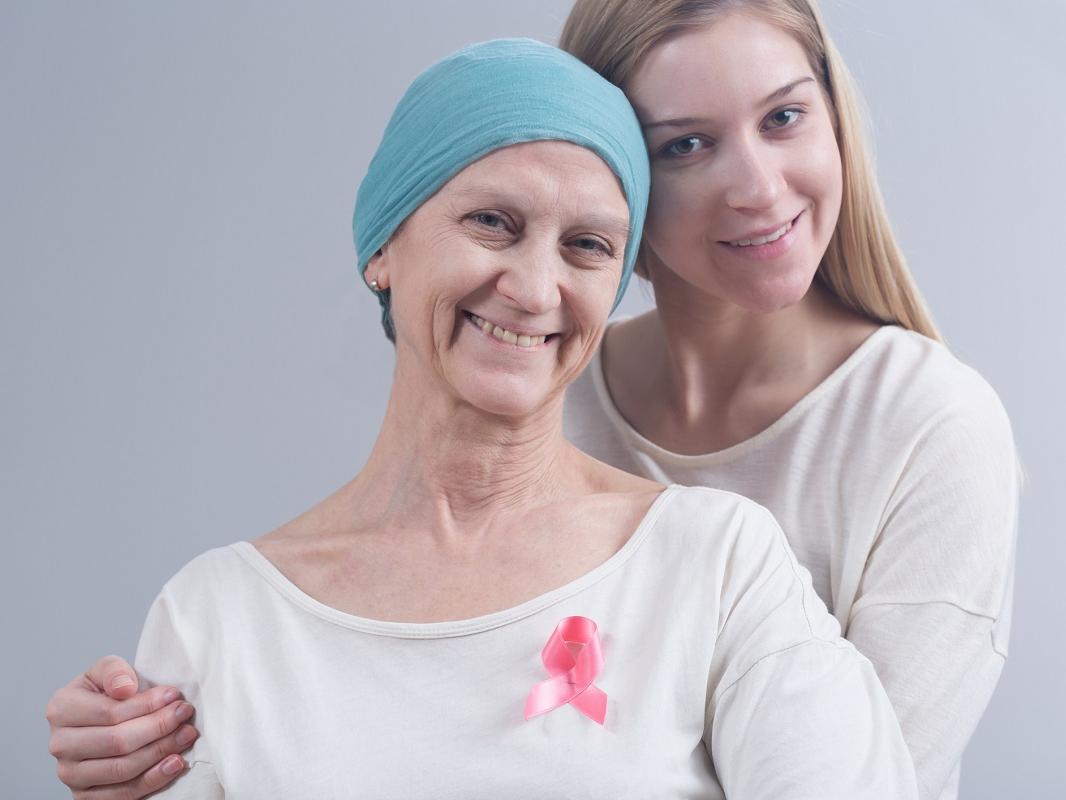 A woman with breast cancer poses with her daughter. Both are smiling.