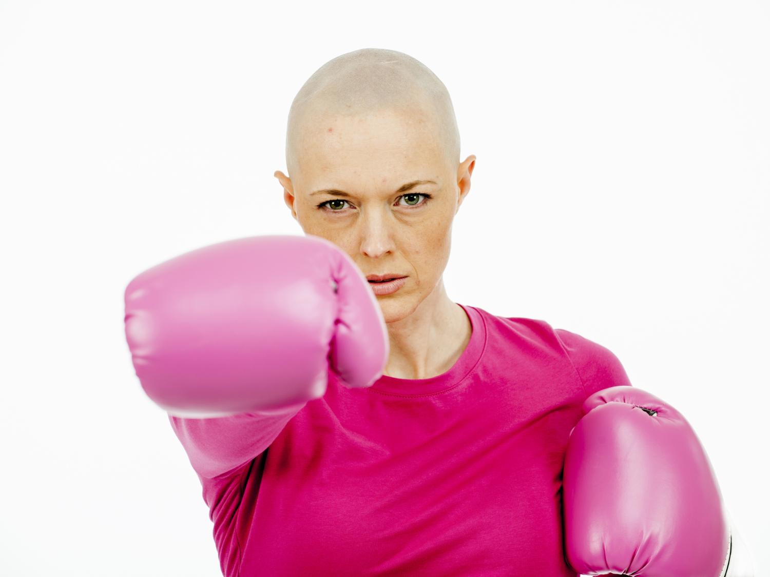 A bald woman dressed in pink punching toward the camera