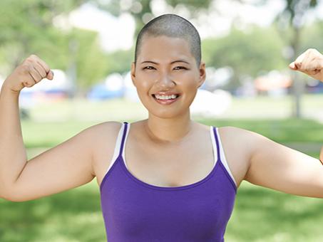 A woman flexes her muscles and smiles.