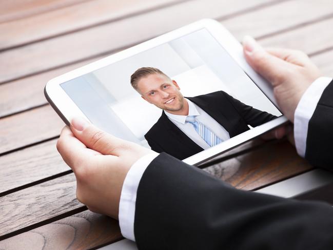 A recruiter talks with a job applicant via a tablet.