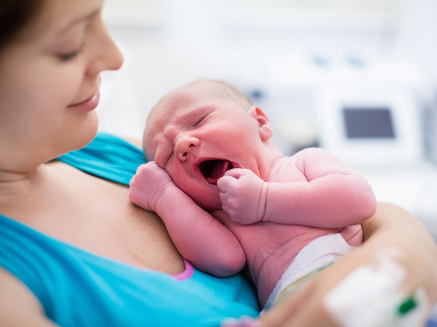 A mother holds a newborn to her chest.