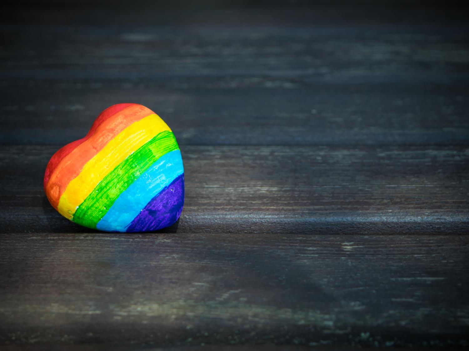 A heart-shaped rock painted with the colors of the rainbow.