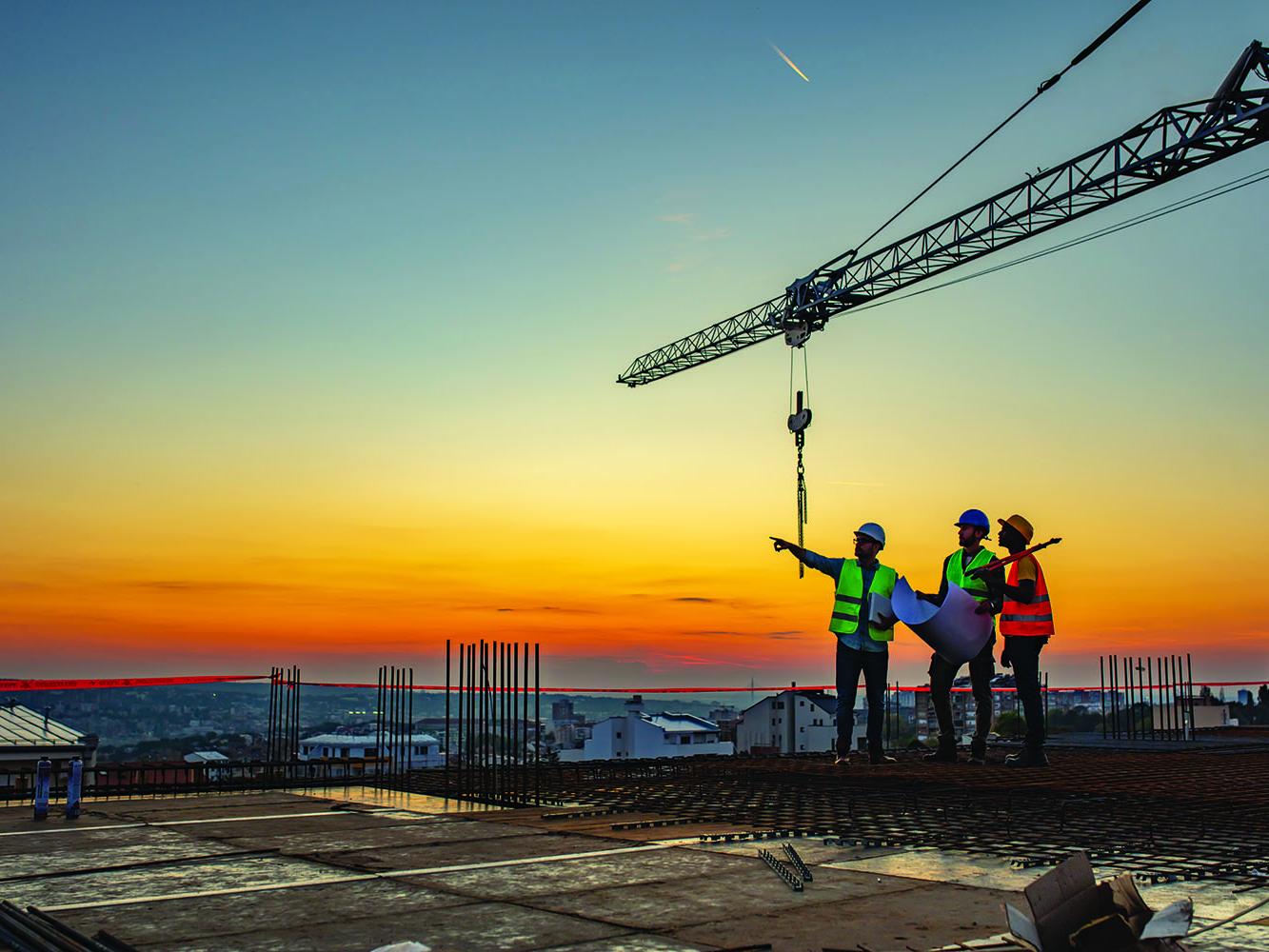 construction managers look at blueprints on top of a building