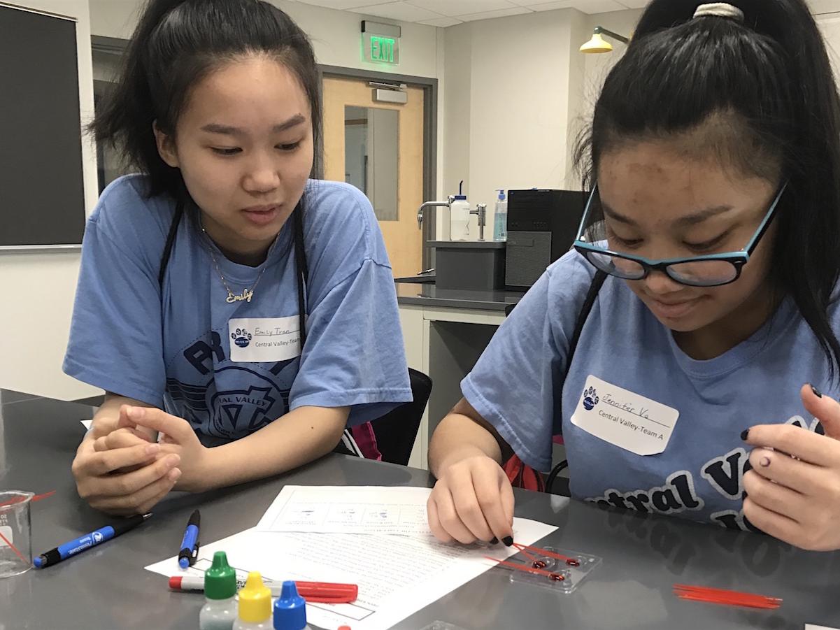 Two female students look at a vile of simulated blood.
