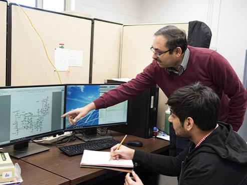 A professor and a student examine a graph on a computer