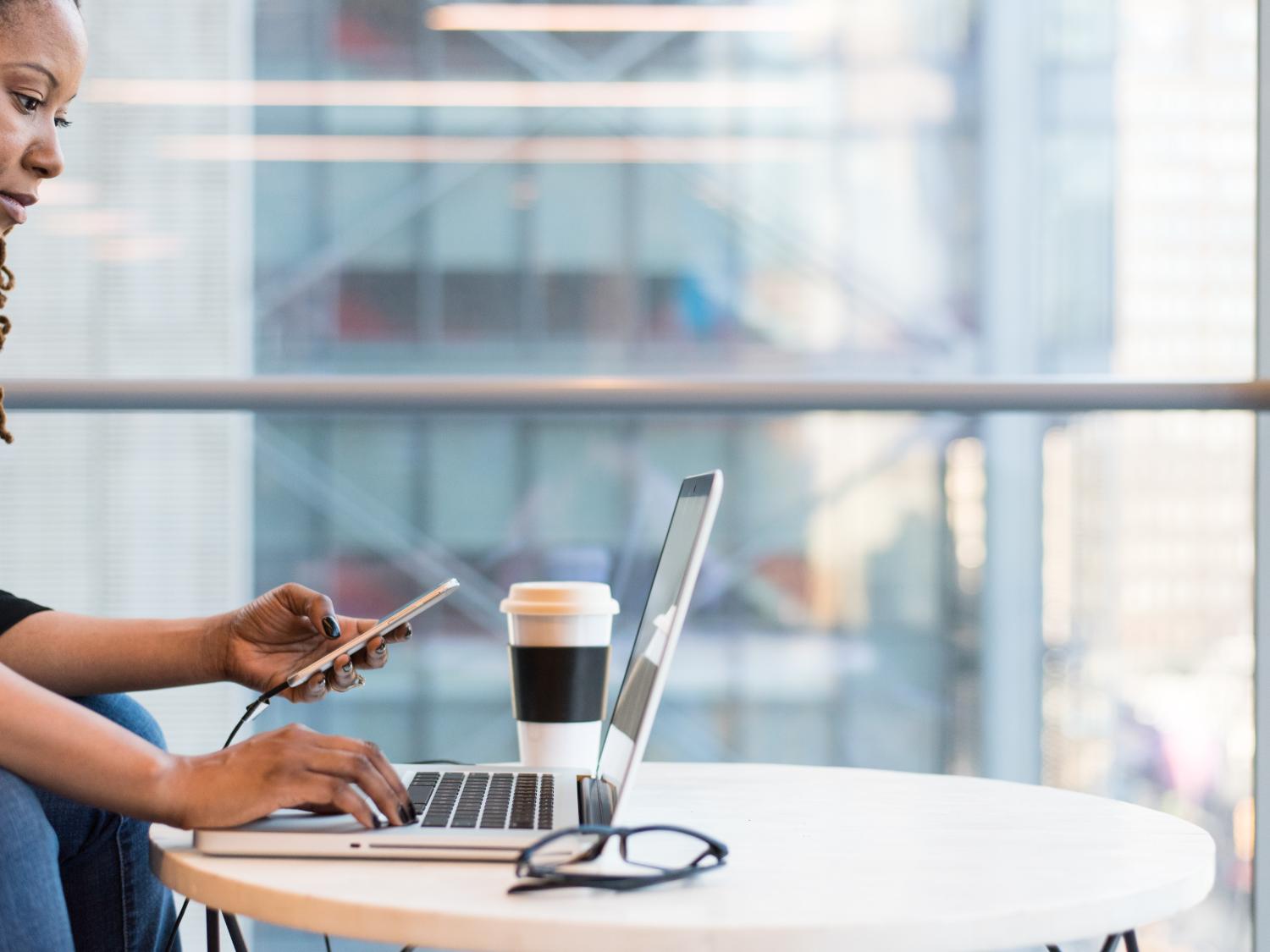 Woman using laptop and phone