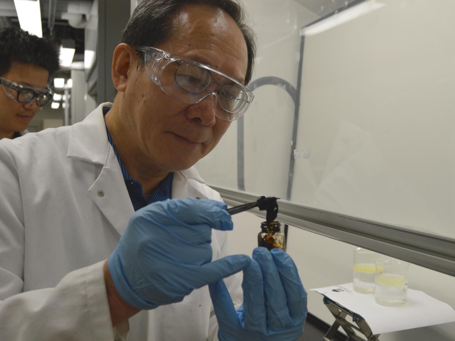 Mike Chung using tweezers to pull absorbed oil/petrogel solid from small glass.