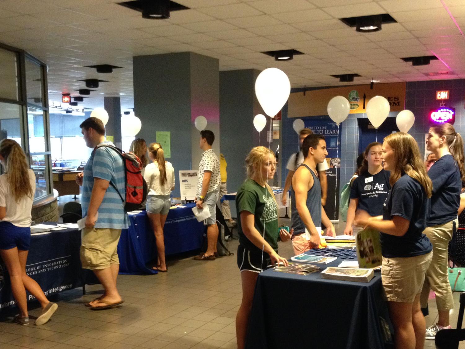 Students attending College Fair talk with college reps at information tables