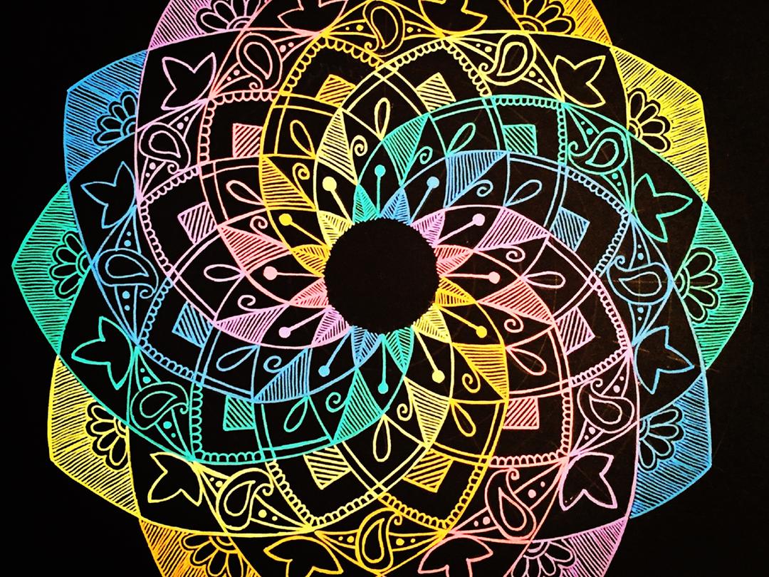 A rainbow-colored, intricate mandala on a black background.