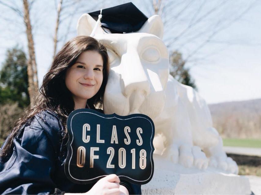Student with cap and gown in front of lion shrine
