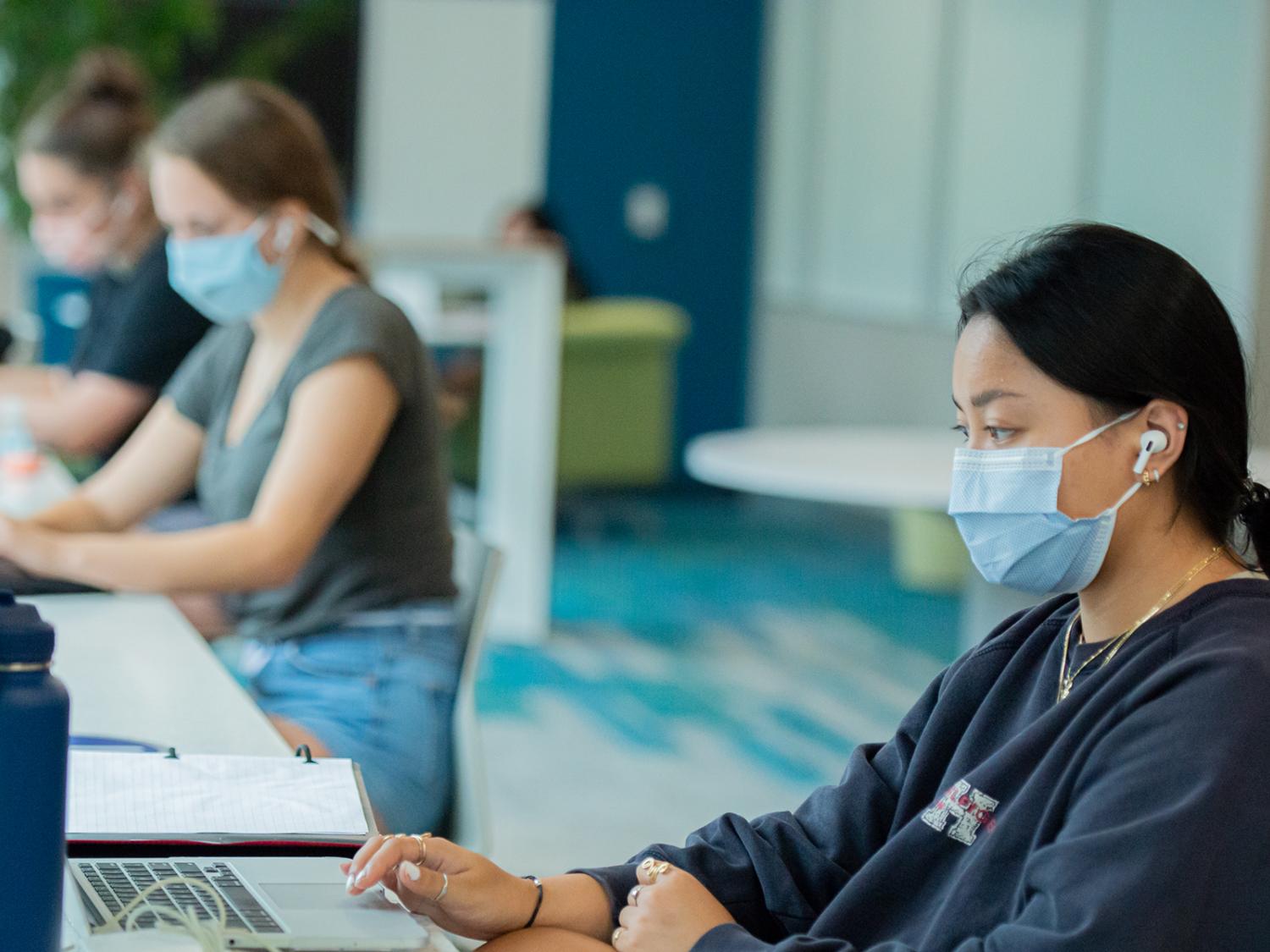 Students wearing masks sitting and doing work at lab computers