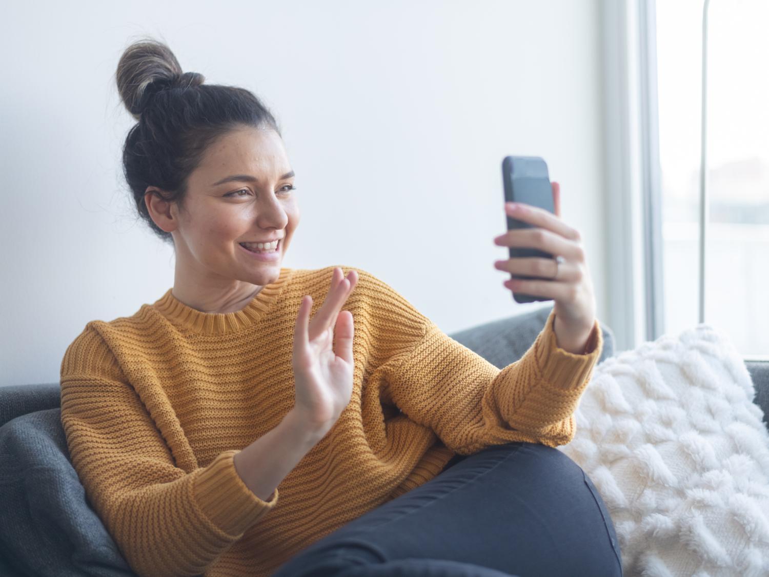 A woman holding a phone and waving at the screen