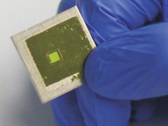 a gloved hand holding Fabricated free-standing metamaterial filter thin-film mounted on an optical frame.