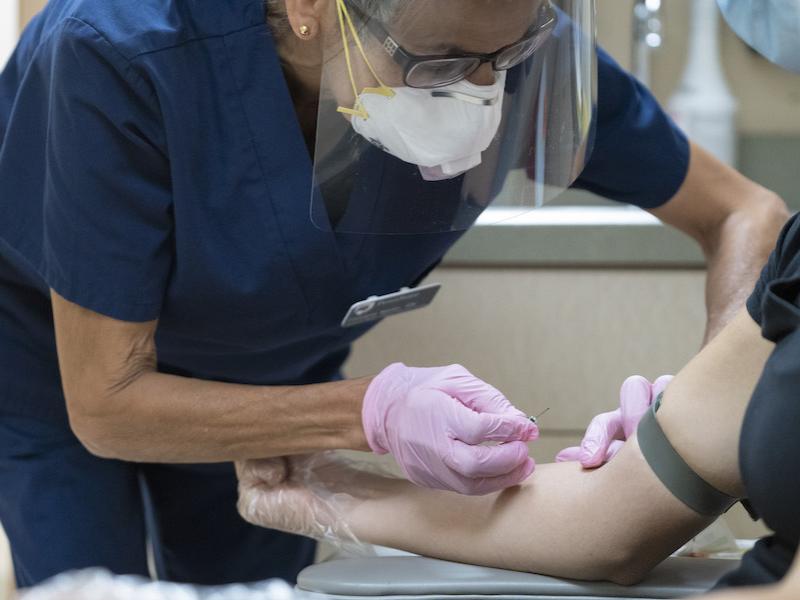 Technician taking a blood sample from project participant.