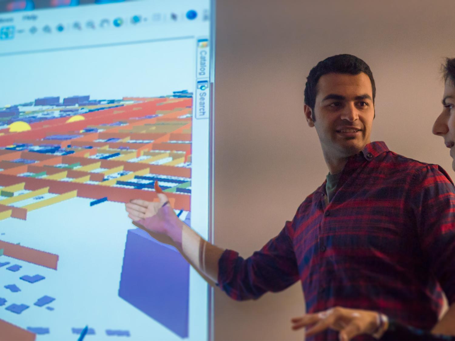 Graduate student and professor stand in front of map projected on screen