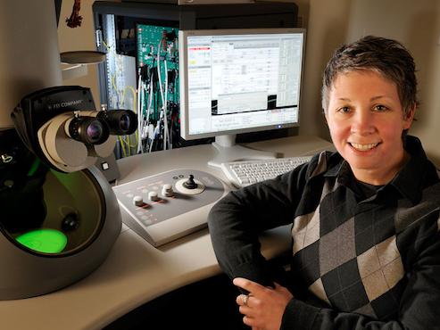 Deb Kelly in lab next to electron microscope, computer screen