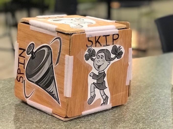 A wooden block held together by velcro and decorated with clip art sits on a table.