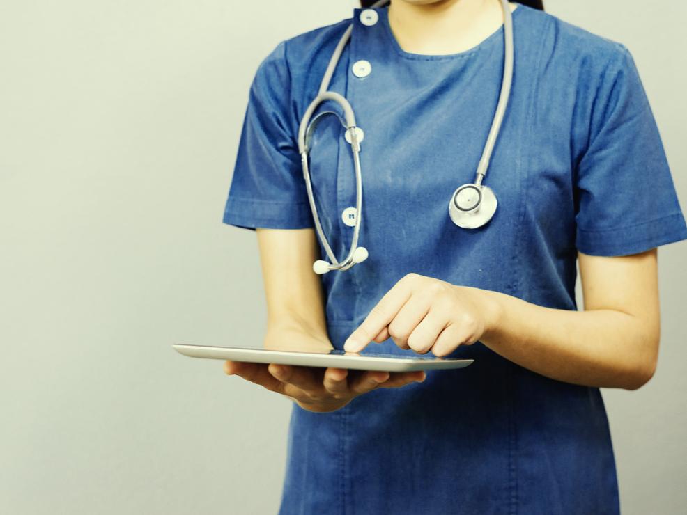 A female doctor enters data onto an iPad as part of a patient's electronic health record