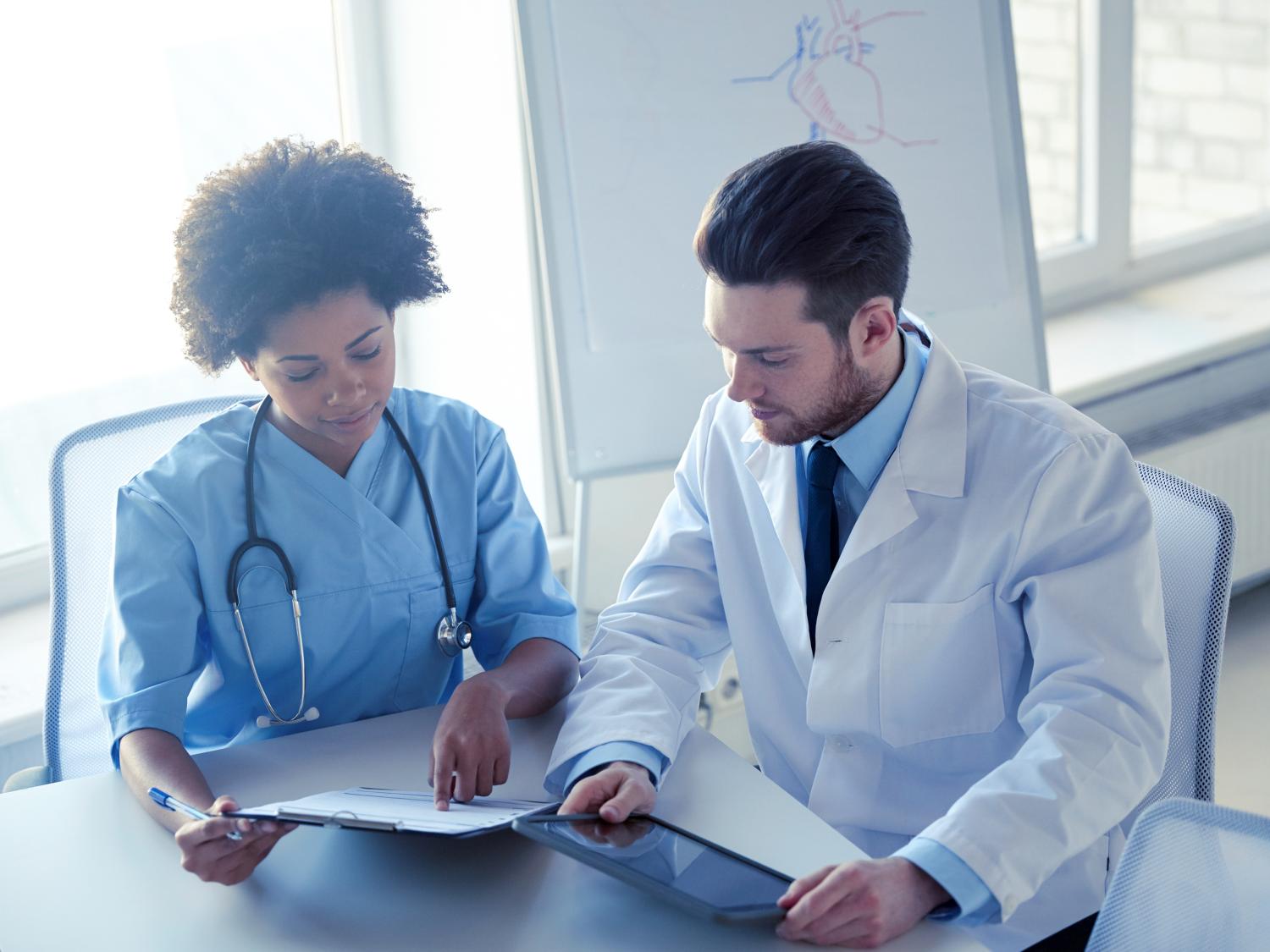Two doctors reading over a tablet.