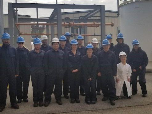 Group of people in blue overalls inside of chemical plant