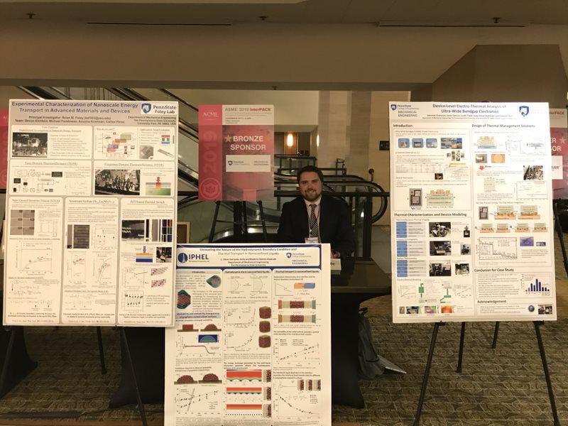 A Caucasian man stands among several research posters.