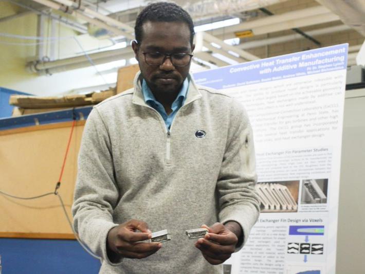 A Sudanese man holds small piece of metal in a lab. 