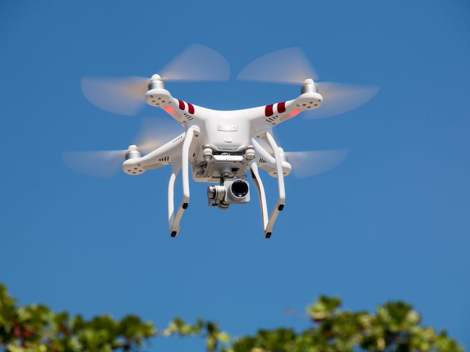 white drone flying in a blue, clear sky