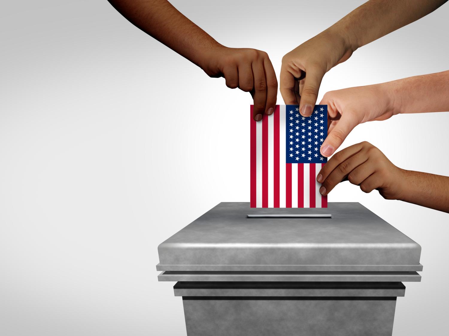 Several hands with different skin tones putting a ballot in a box