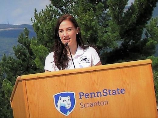 emily scarfo at a podium speaking at a campus event