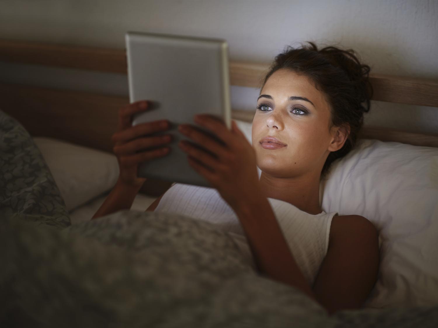 woman reading on iPad in darkened room